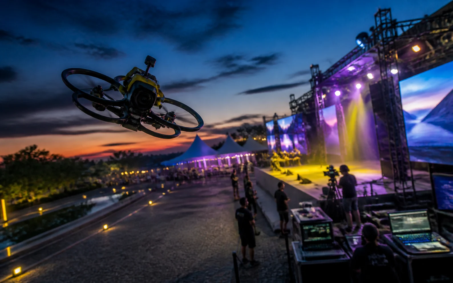 Drone FPV cubriendo un evento exterior con escenario y producción técnica